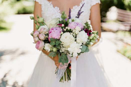 Wedding bouquet with white roses, peonies and green leaves. Bride in dress holds bouquet. Advert for wedding agency