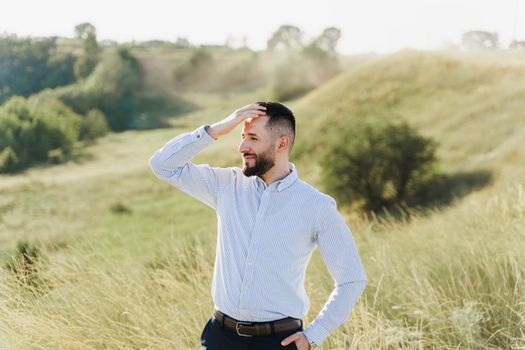 Handsome bearded arabian man in sunglasses on the green hills background. Confident muslim business man. Arab man weared in white shirt