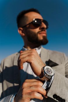 Handsome bearded arabian man in sunglasses on the blue sky background. Confident muslim business man. Arab man weared in grey coat