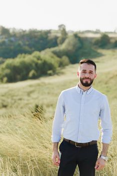 Handsome bearded arabian man in sunglasses on the green hills background. Confident muslim business man. Arab man weared in white shirt