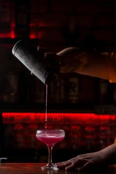 Classic Pink Lady cocktail closeup with flower and cherry on bar counter