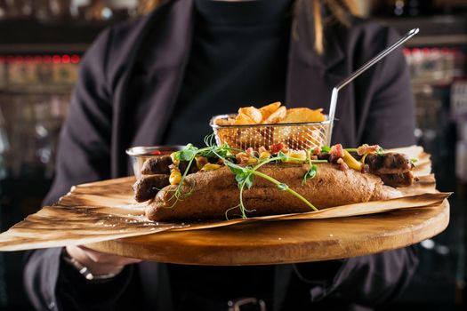 Barbecue grilled hot dog with yellow mustard and ketchup on wooden background. Hot dog sandwich with potato fries and sauces