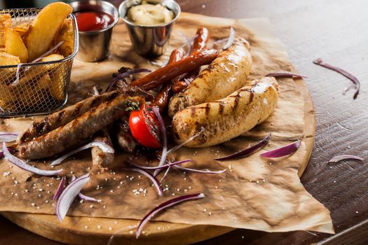 Barbecue grilled hot dog with yellow mustard and ketchup on wooden background. Hot dog sandwich with potato fries and sauces.