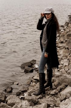 Young woman with curly hair looks at the lake and dreams about her life