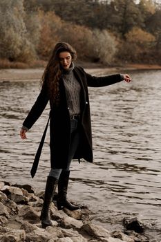 Young woman with curly hair looks at the lake and dreams about her life