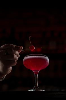 Classic Pink Lady cocktail closeup with flower and cherry on bar counter