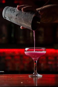 Classic Pink Lady cocktail closeup with flower and cherry on bar counter