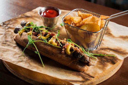 Barbecue grilled hot dog and beer with yellow mustard and ketchup on wooden background. Hot dog sandwich with potato fries and sauces.