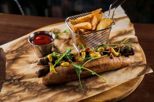 Barbecue grilled hot dog and beer with yellow mustard and ketchup on wooden background. Hot dog sandwich with potato fries and sauces.