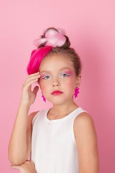 charming little girl with pink hairstyle and pink makeup. tween young model posing on pink background.