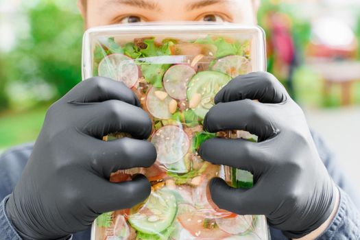 Green salad with veal, vagatables, microgreen. Safety delivery in medical gloves at quarantine covid 19. Salad in eco thermo box