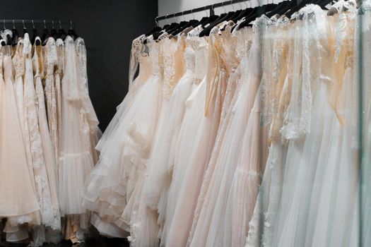 Wedding dresses made of silk chiffon, tulle and lace. Beautiful White cream bridal dress on hangers in wedding salon.
