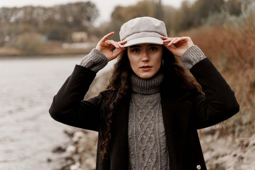 Young woman with curly hair looks at the lake and dreams about her life