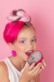 sweet Girl is holding a Pitahaya near her face. A pitaya fruit hold in hand on pink background. Tropical Dragon Fruit cut in half. space for text