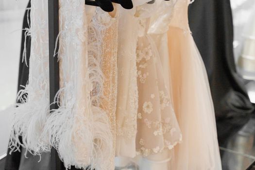 Little wedding dress for child on hangers made of silk chiffon, tulle and lace. White cream bridal dress for little princess. Pearls and crystals pendants on the sleeves of a wedding dress