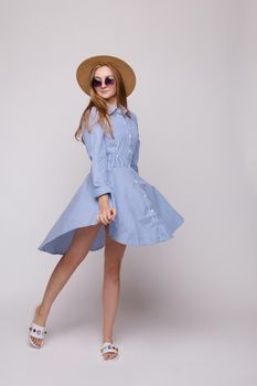 Front view of bright young girl wearing straw hat and glasses posing on isolated background in studio. Female tourist, looking at camera and smiling. Concept of summer.