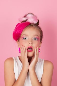 charming little girl with pink hairstyle and pink makeup. tween young model posing on pink background.