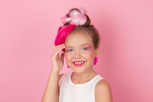 charming little girl with pink hairstyle and pink makeup. tween young model posing on pink background.