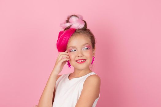 charming little girl with pink hairstyle and pink makeup. tween young model posing on pink background.