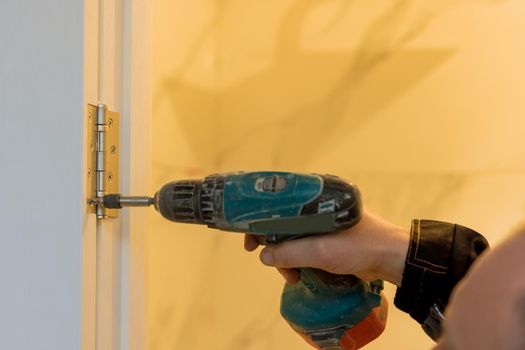 Handyman using a screwdriver drill to installing lock in door in a house