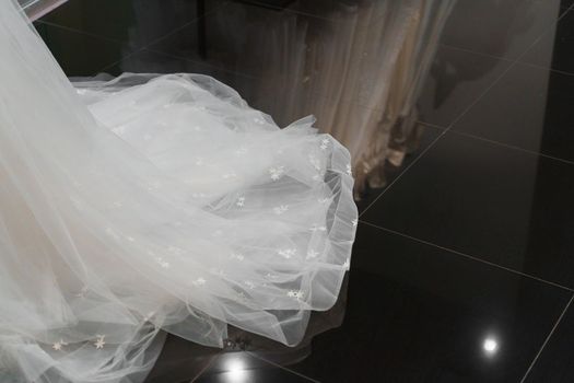 Wedding dress made of silk chiffon, tulle and lace. Beautiful White cream bridal dress on hangers in wedding salon. Photo with empty space right side for text of advertise