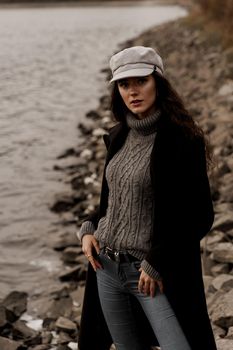 Young woman with curly hair looks at the lake and dreams about her life