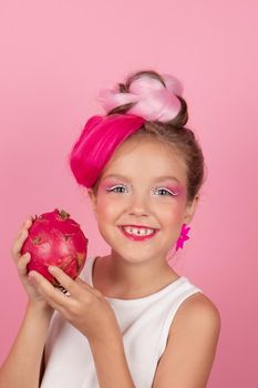 sweet Girl is holding a Pitahaya near her face. A pitaya fruit hold in hand on pink background. Tropical Dragon Fruit cut in half. space for text