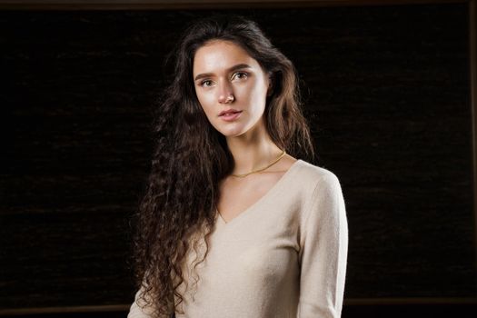 Fashion model posing in studio isoleted on black background. Lifestyle of pretty girl. Happy lady weared brown pullover.