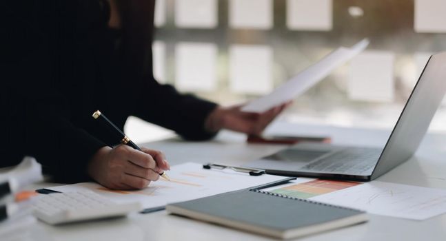 Close up of businesswoman or accountant hand holding pen working on business financial data, accountancy document and calculator at office..