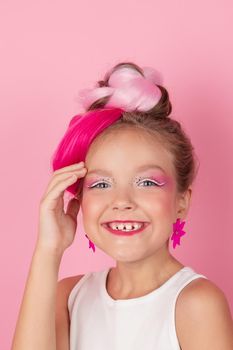 charming little girl with pink hairstyle and pink makeup. tween young model posing on pink background.