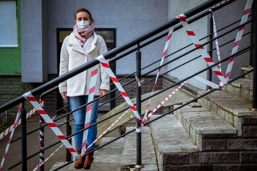 Photo of a girl in a mask. Standing on the street with danger warning tapes. isolated Covid-19 pandemic.