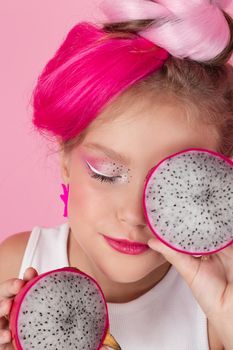 sweet Girl is holding a Pitahaya near her face. A pitaya fruit hold in hand on pink background. Tropical Dragon Fruit cut in half. space for text