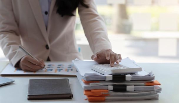 Businesswoman using calculator working at office with reports document financial..