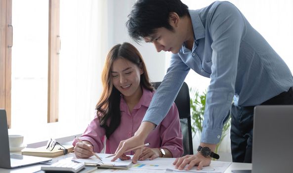 Two Cheerful Asian young business people working together using a tablet at a modern office.doing planning analyzing the financial report, business plan investment, finance analysis concept.