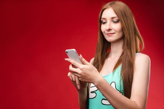 Studio portrait of beautiful caucasian brunette woman in patterned overall pointing at her smartphone with index finger. She is certain or sure about something. I know gesture.