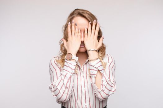 Fashion casual business woman posing closing face by hand isolated at white studio background medium shot. Scared young European female touching eyes by arm and open mouth having stress