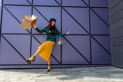 A happy shopaholic girl throws her bags near a shopping center. Have fun shopping on Black Friday. the girl in the store is happy with her purchases, throws packages. Consumer concept