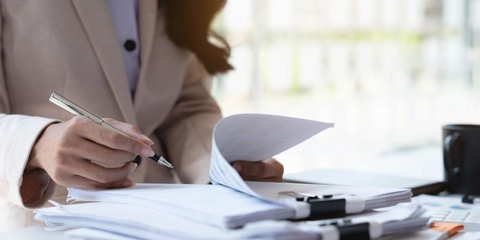 Businesswoman pointing pen at data graph, estimating profit and income statement of business in office..