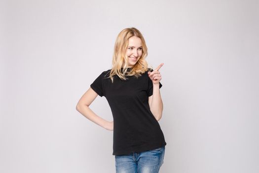 Studio portrait of beautiful caucasian brunette woman in patterned overall pointing at her smartphone with index finger. She is certain or sure about something. I know gesture.