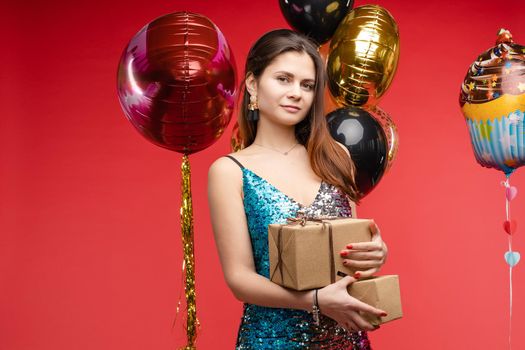 Full length studio portrait in sexy sparkling cocktail dress with red lips. She is posing with lips air balloon. Isolate on red background.