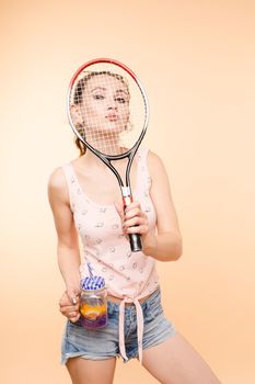 Active young girl in t-shirt and shorts holding racket in hand. Brunette lady with sunglasses on head enjoying drink after playing tennis. Beautiful woman relaxing and drinking lemonade after game.