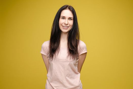 Pretty blonde haired woman wearing in black sweater, holding messy unbrushed hair in one hand and pink hairbrush in another one. A frustrated girl looks at her hair on a white studio background.