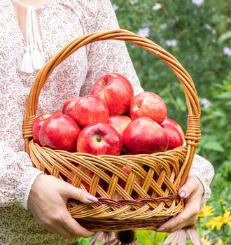 Woman holding a wicker basket with a red apples