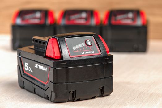 Battery for cordless drill. Screwdriver battery. Four batteries with a charge indicator lie on a wooden background.