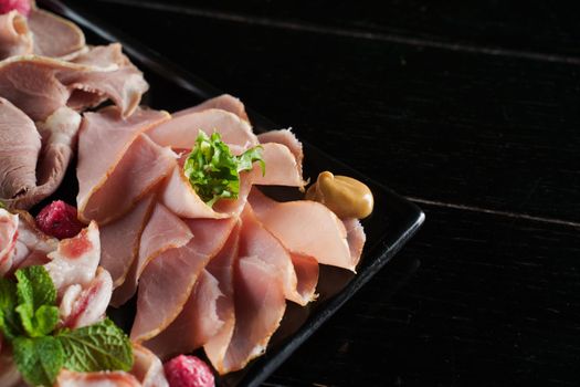 Charcuterie board close-up with cured meat. Smoked meat ot the black plate