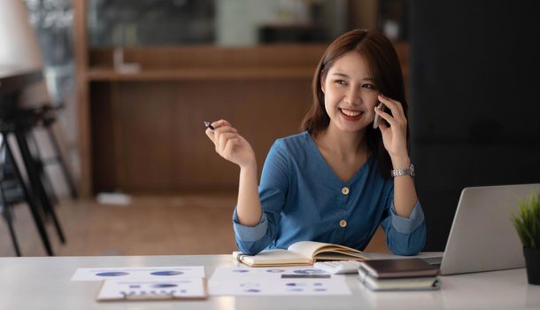 Business asian woman using smartphone for do math finance on wooden desk in office, tax, accounting, financial concept.