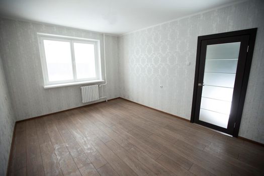Empty room with laminate floors with white walls and window