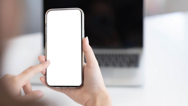 Cropped shot view of woman hands holding smart phone with blank copy space screen for your text message or information content, female reading text message on cell telephone during in office..