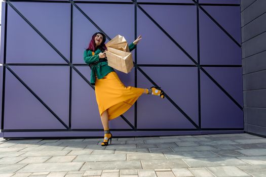 A happy shopaholic girl throws her bags near a shopping center. Have fun shopping on Black Friday. the girl in the store is happy with her purchases, throws packages. Consumer concept