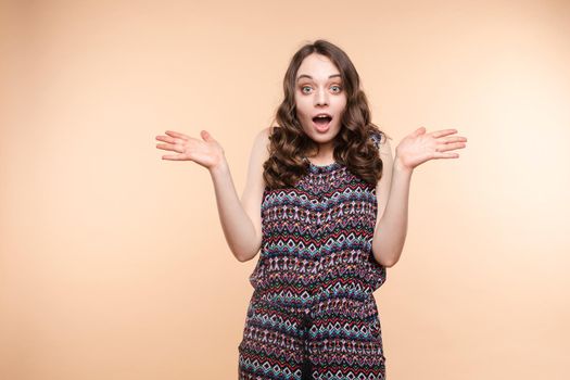 Waist up portrait of surprised beautiful girl with nice long hair, perfect makeup and fashion manicure. She is looking at camera with astonishment. Isolated on dark background